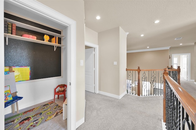 hallway with light colored carpet and a textured ceiling