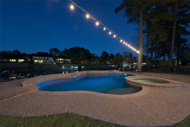 pool at night featuring an in ground hot tub and a patio