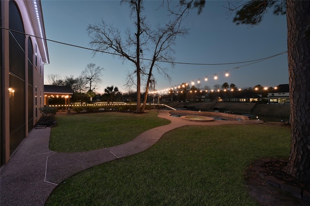 yard at dusk featuring a hot tub