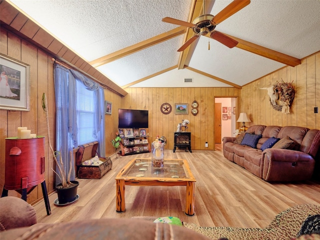 living room with vaulted ceiling with beams, hardwood / wood-style flooring, and a textured ceiling