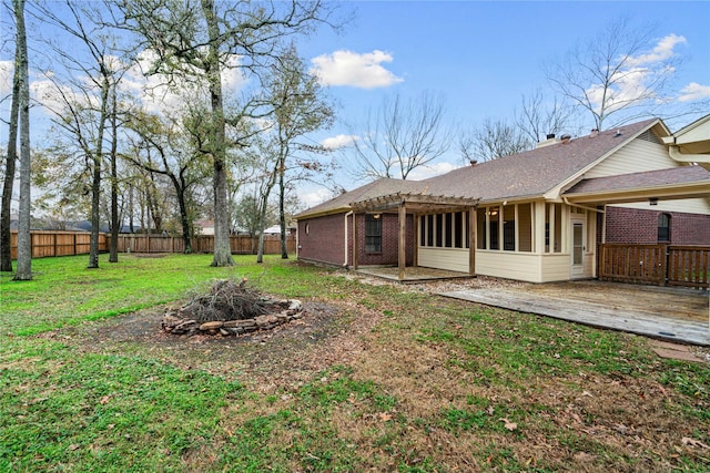 rear view of property with a yard, a deck, and an outdoor fire pit