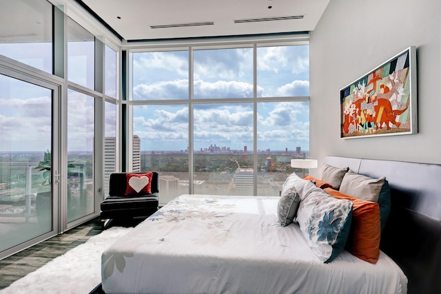 bedroom featuring wood-type flooring, access to outside, and a wall of windows