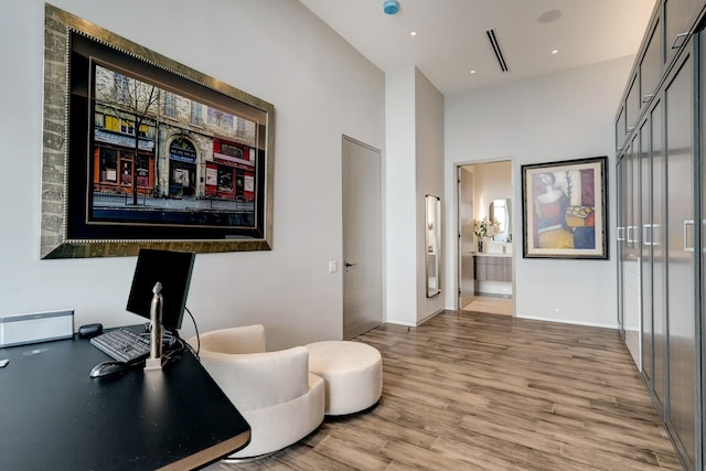 home office featuring light hardwood / wood-style flooring and a high ceiling