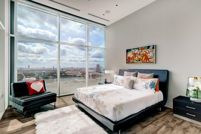 bedroom with hardwood / wood-style floors and a wall of windows