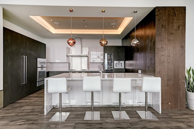 kitchen with white cabinetry, a breakfast bar, and a raised ceiling