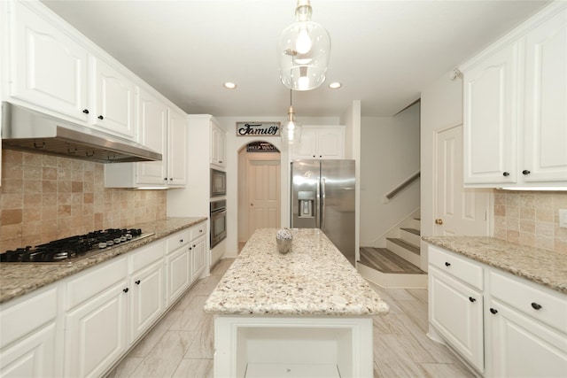 kitchen featuring light stone counters, appliances with stainless steel finishes, hanging light fixtures, and a kitchen island