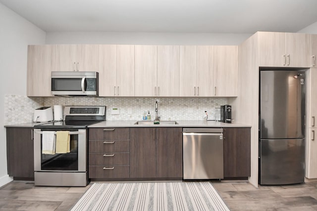 kitchen featuring tasteful backsplash, stainless steel appliances, sink, and light hardwood / wood-style flooring