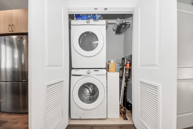 laundry room with wood-type flooring and stacked washer / drying machine