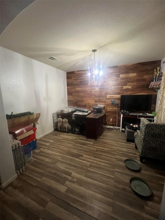 interior space featuring dark wood-type flooring, an inviting chandelier, and wood walls