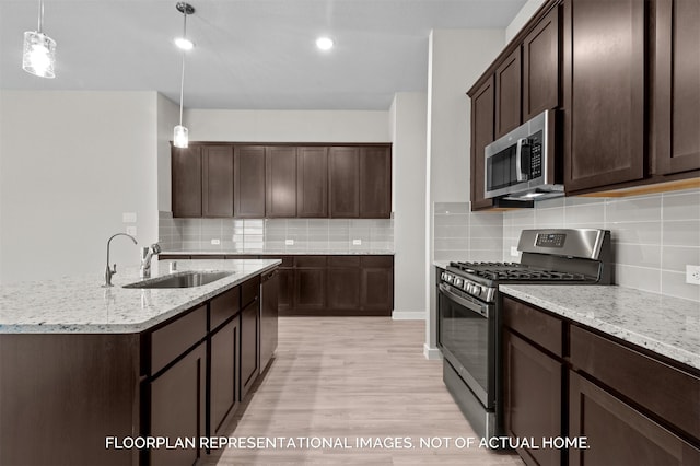 kitchen featuring pendant lighting, sink, appliances with stainless steel finishes, dark brown cabinets, and light stone countertops