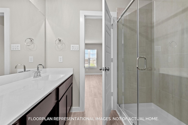 bathroom featuring a stall shower, wood finished floors, vanity, and baseboards