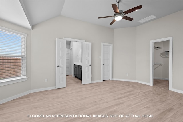 unfurnished bedroom featuring lofted ceiling, visible vents, baseboards, a spacious closet, and light wood finished floors