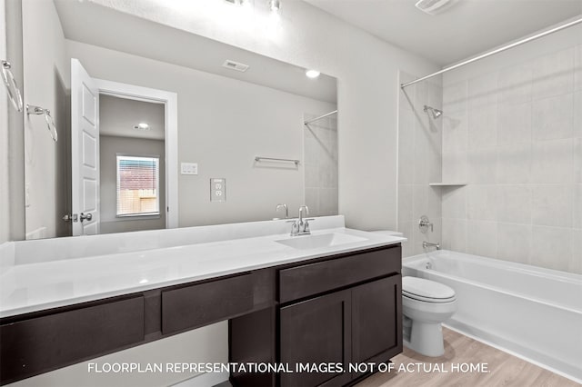 bathroom featuring visible vents, toilet, wood finished floors, tub / shower combination, and vanity