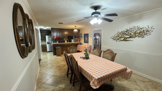 dining area featuring ornamental molding, a textured ceiling, and light tile patterned flooring