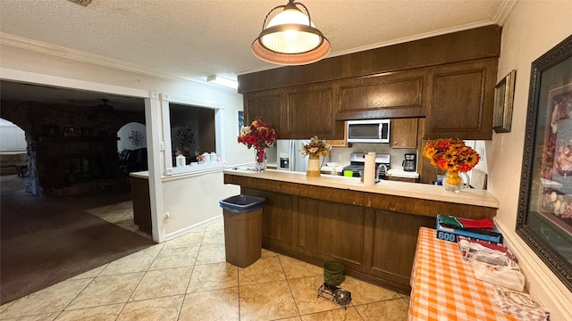 kitchen with light tile patterned flooring, a textured ceiling, ornamental molding, appliances with stainless steel finishes, and kitchen peninsula