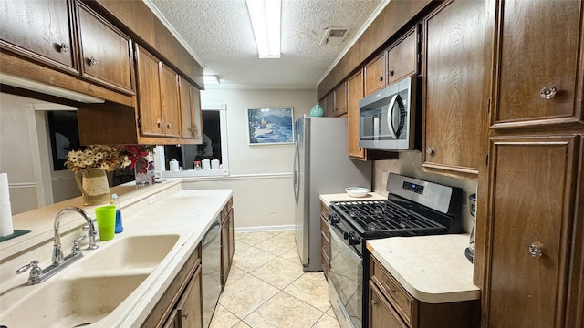 kitchen featuring sink, light tile patterned flooring, a textured ceiling, and appliances with stainless steel finishes