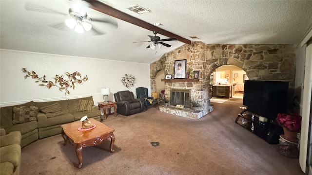 carpeted living room featuring ceiling fan, a stone fireplace, lofted ceiling with beams, and a textured ceiling