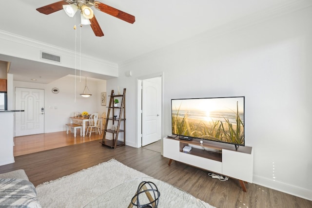 living room with crown molding, ceiling fan, and dark hardwood / wood-style floors