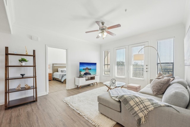 living room with crown molding, ceiling fan, and light hardwood / wood-style flooring