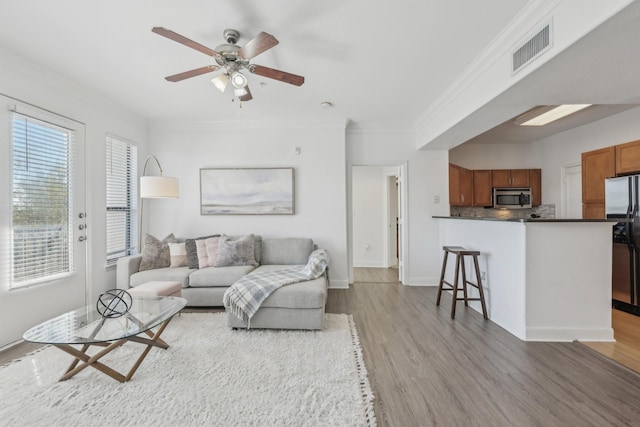 living room with crown molding, ceiling fan, and light hardwood / wood-style flooring