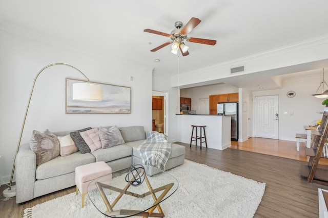 living room with hardwood / wood-style floors, crown molding, and ceiling fan