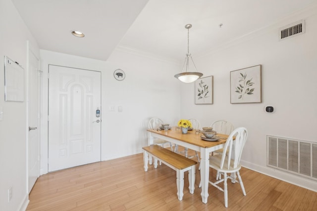 dining space with crown molding and light wood-type flooring