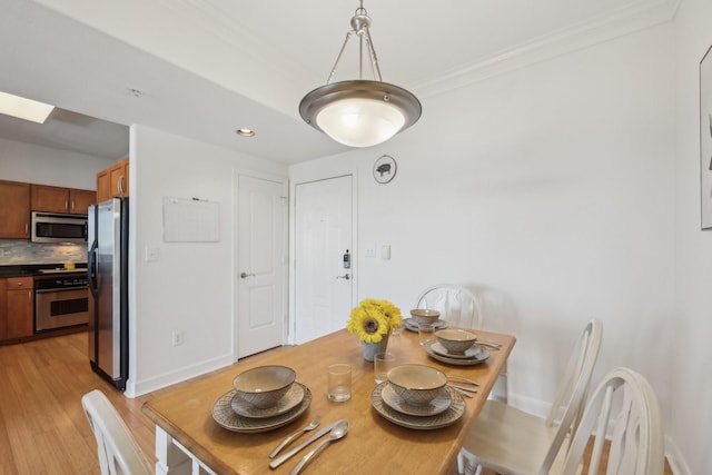 dining space with crown molding, light hardwood / wood-style floors, and a skylight