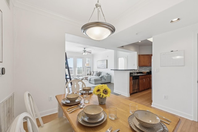 dining space featuring crown molding, sink, ceiling fan, and light wood-type flooring