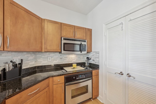 kitchen with dark stone countertops, decorative backsplash, and stainless steel appliances