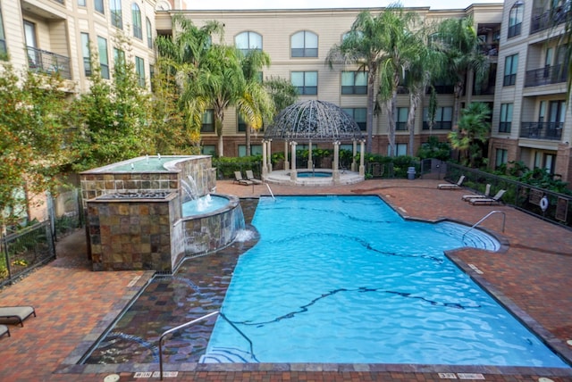 view of swimming pool with a gazebo, pool water feature, and a community hot tub