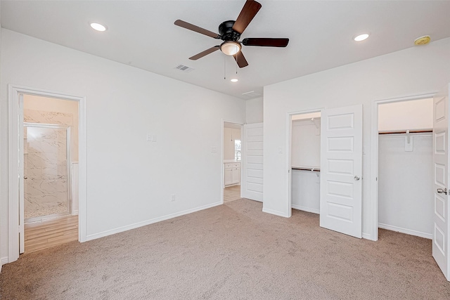 unfurnished bedroom with light carpet, ceiling fan, and multiple closets