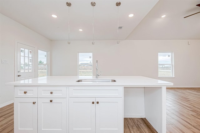 kitchen with white cabinetry, sink, hanging light fixtures, and a center island with sink