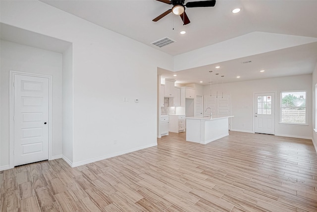 unfurnished living room with ceiling fan, lofted ceiling, sink, and light wood-type flooring