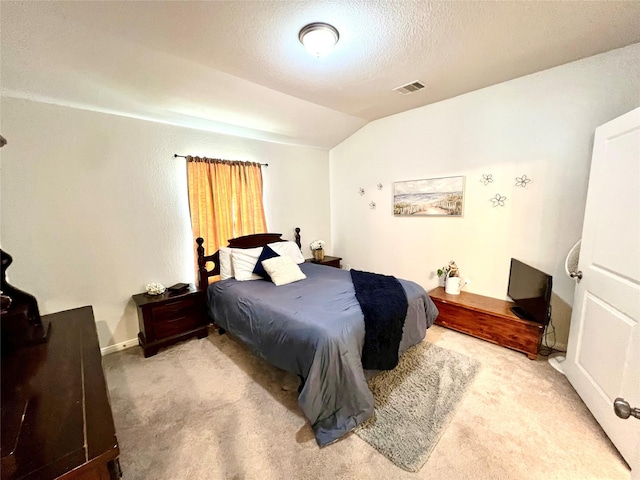 bedroom featuring vaulted ceiling, light carpet, and a textured ceiling