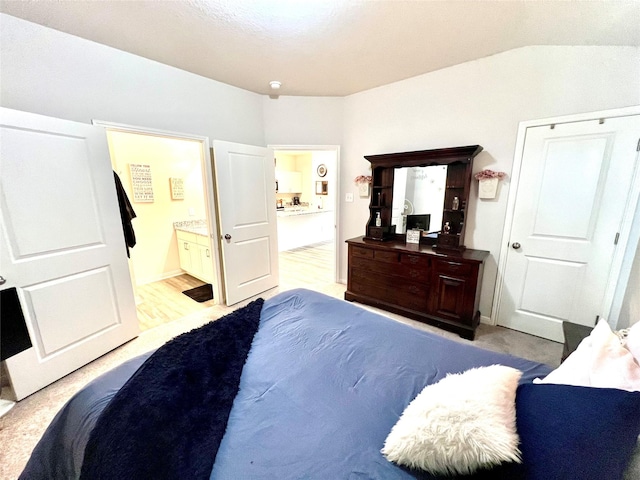 bedroom featuring vaulted ceiling and ensuite bathroom