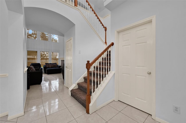 stairway featuring a towering ceiling and tile patterned floors