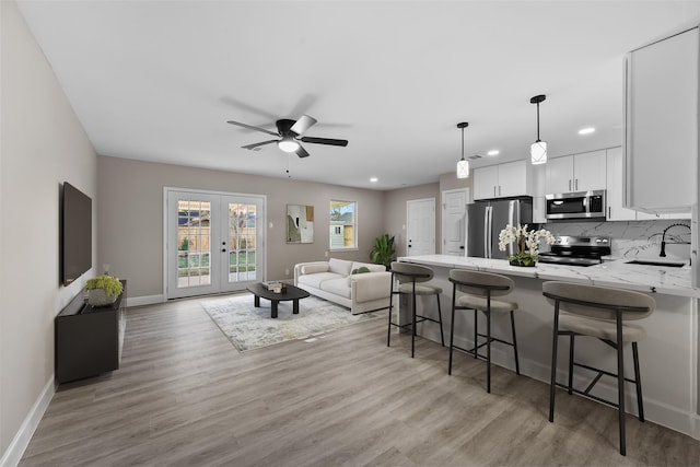 kitchen with appliances with stainless steel finishes, a kitchen breakfast bar, white cabinets, french doors, and kitchen peninsula