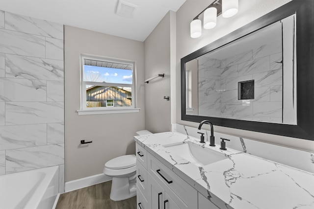 full bathroom with tiled shower / bath combo, vanity, hardwood / wood-style floors, and toilet