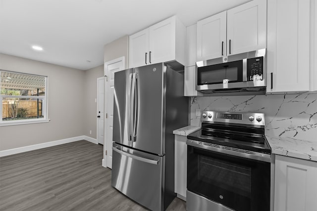 kitchen with appliances with stainless steel finishes, light stone counters, white cabinets, dark hardwood / wood-style flooring, and decorative backsplash