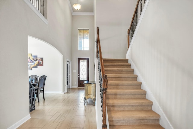 stairs with crown molding and a towering ceiling