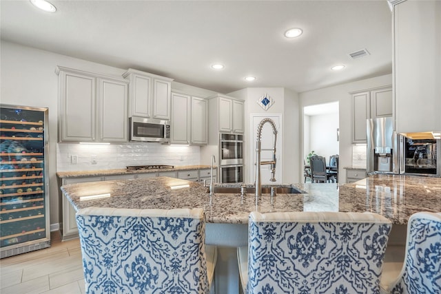 kitchen featuring a breakfast bar area, stainless steel appliances, kitchen peninsula, and beverage cooler