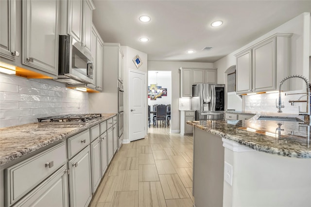 kitchen with stainless steel appliances, stone countertops, sink, and gray cabinets