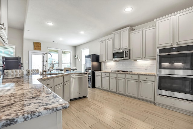 kitchen featuring appliances with stainless steel finishes, tasteful backsplash, sink, white cabinets, and light stone counters