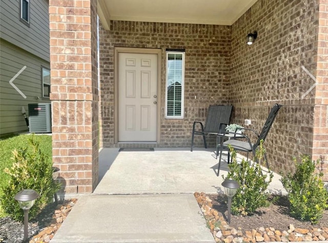 view of exterior entry with a patio and cooling unit