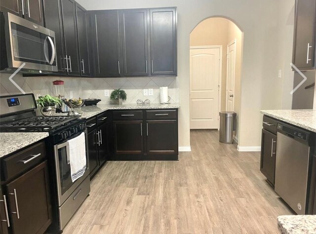 kitchen featuring light stone counters, tasteful backsplash, stainless steel appliances, and light hardwood / wood-style floors