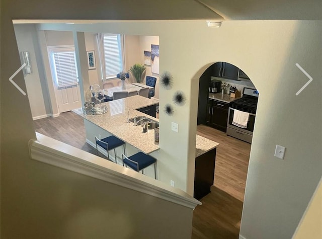 kitchen with gas stove, light stone countertops, and hardwood / wood-style floors