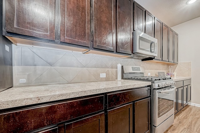 kitchen with stainless steel appliances, light wood-type flooring, dark brown cabinetry, and decorative backsplash