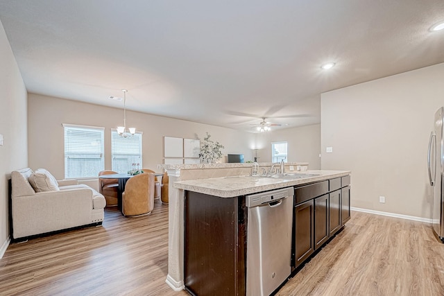 kitchen with appliances with stainless steel finishes, pendant lighting, an island with sink, sink, and dark brown cabinetry