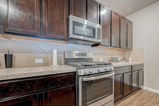 kitchen featuring dark brown cabinetry, decorative backsplash, light wood-type flooring, and appliances with stainless steel finishes