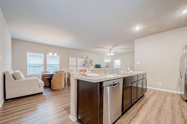 kitchen featuring dark brown cabinetry, sink, hanging light fixtures, appliances with stainless steel finishes, and an island with sink